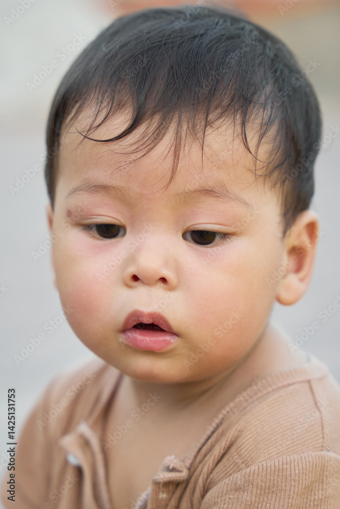 The baby is looking at the camera, and it appears that he is not happy about something. The baby's facial expression suggests that he might be crying or upset. The baby is looking at the camera, and it appears that he is not happy about something. The baby's facial expression suggests that he might be crying or upset.