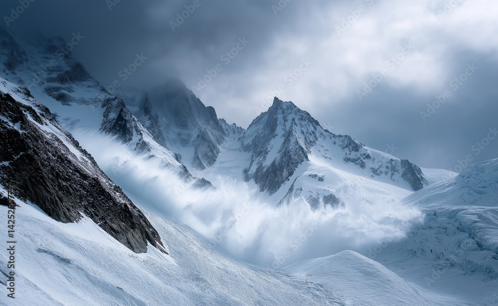 Obraz premium Snow-covered mountain peaks shrouded in mist and clouds during a dramatic winter storm. 