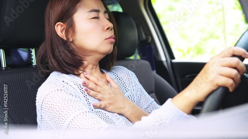 asian woman having a panic attack while driving her car, feeling scared and anxious, trying to calm herself down by taking deep breaths and staying focused to drive safely