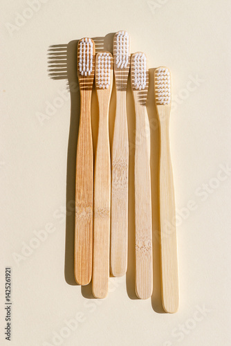 Obraz na płótnie Eco friendly Bamboo toothbrushes with white bristles at sunlight with dark shadows on beige background. Sustainable living concepts, minimal style aesthetic photo, top view set wooden brushes w salonie