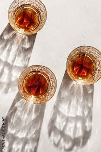 Obraz na płótnie Crystal Whiskey Glasses with shadows at sunlight on beige textured background, minimal aesthetic flat lay shiny glasses, sun glare, stong alcohol drink concept, summer still life top view, copyspace w salonie