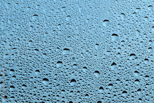 Water drops on the glass, blue sky texture background..Rain drops on window glass. Natural Pattern of raindrops.