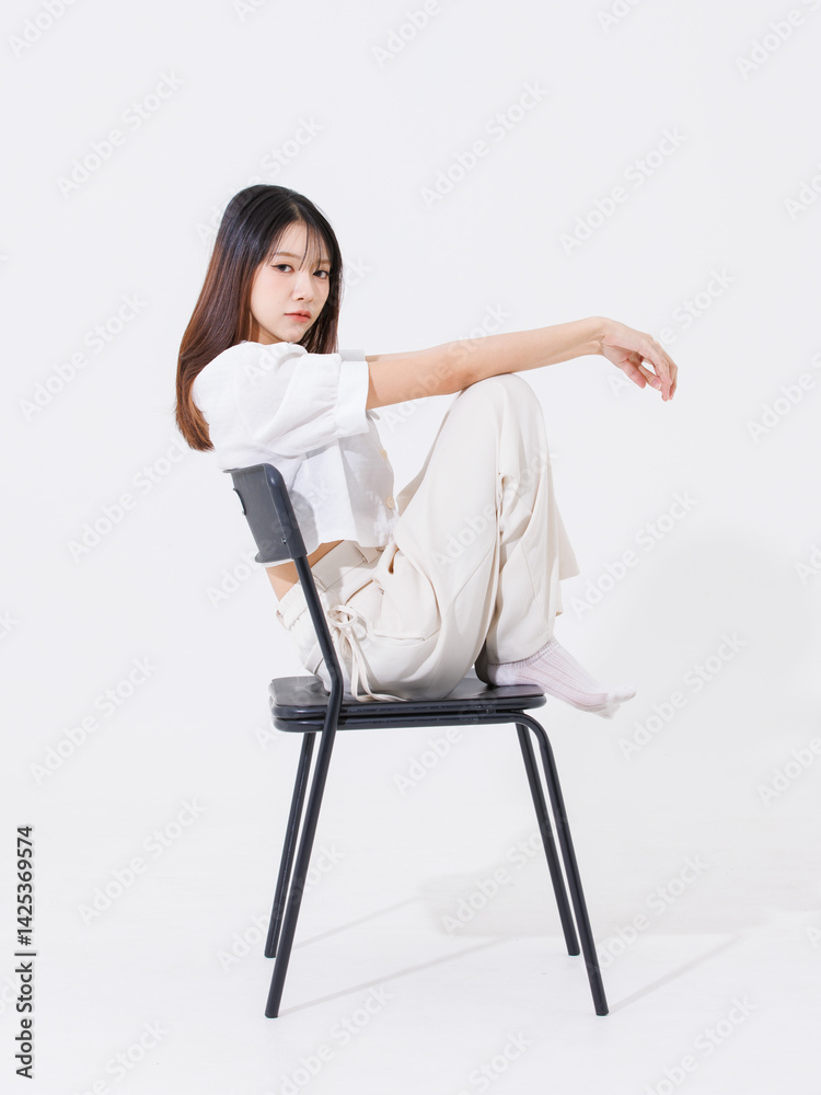Fototapeta premium Asian young beautiful pretty happy woman she smiling, cute friendly wearing white shirt white pants sitting on black chair pose isolated on white background studio portrait. Lifestyle fashion concept.