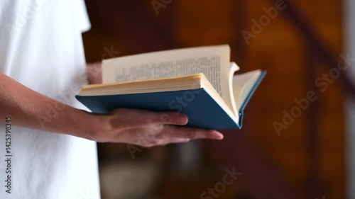 A woman in a white T-shirt flips through and reads a close-up blue book. High quality FullHD footage