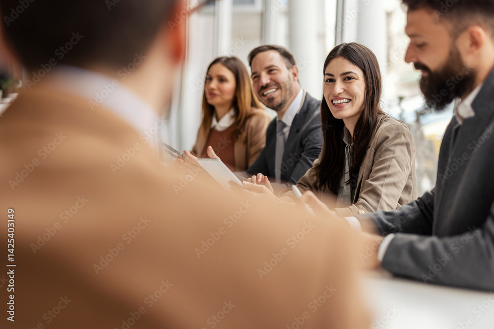 Selective focus on smiling businesswoman sitting at meeting room surrounded by colleagues.