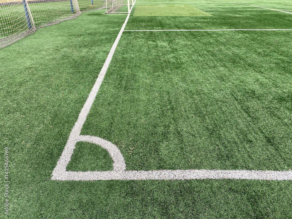 Obraz premium Artificial green grass, football field surface. Corner kick marking lines. Public soccer field.
