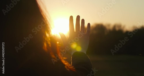 silhouette woman practicing mindfulness at sunset, her hand reaching out to capture the sun s rays. mindfulness scene represents awareness, calm, and meditation in peaceful nature.