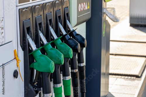 Close-up of fuel pump nozzles at gas station. Detailed view of multiple green and black fuel pump nozzles at a modern gas station, showing refueling equipment and energy concept. photo