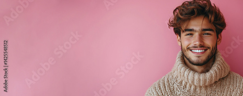 Obraz na płótnie Cheerful young man with tousled hair wearing cozy knitted sweater smiling brightly in front of pink background with copy space Generative AI w salonie