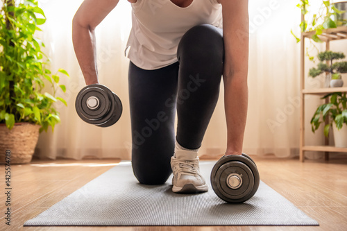 Foto Kneeling on a fitness mat, a mature woman lifting dumbbells engages in a dedicat