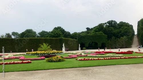 People walking around manicured gardens on the grounds of a Palace. The stunning gardens of Schonbrunn Palace, Vienna, Austria. Europe.