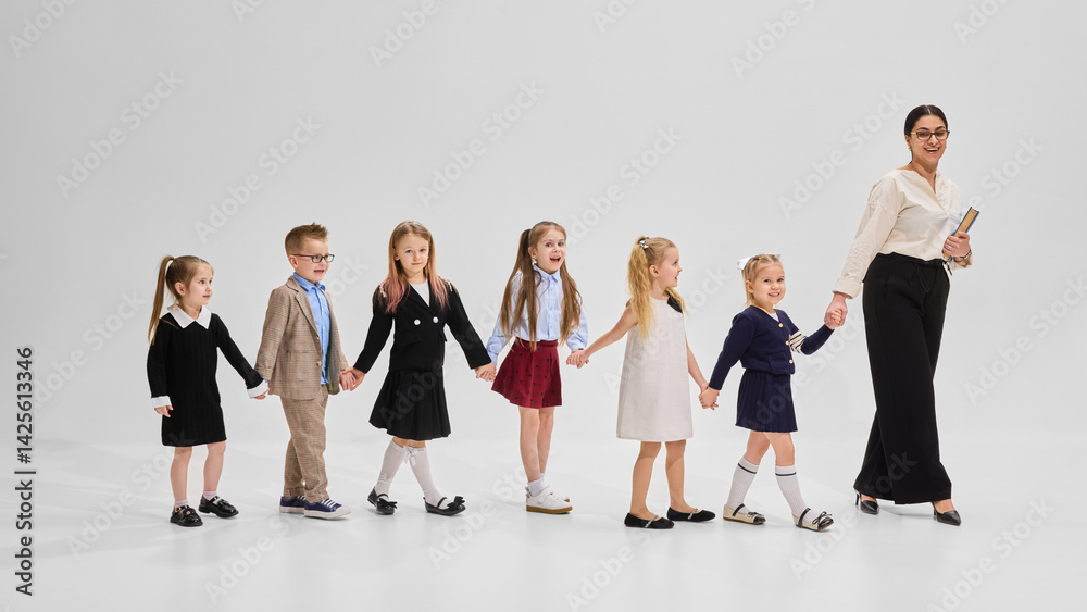 Obraz premium School children smiling and bonding in group portrait with books and teacher against white background. Concept of academic, study, student-teacher connection, early education, back to school.