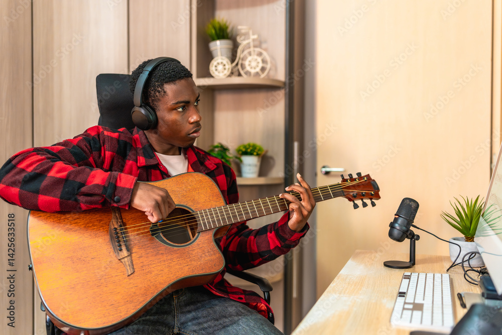 Young musician composing music playing acoustic guitar and recording with a microphone at home