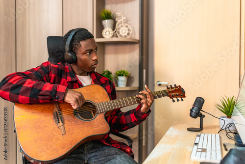Obraz na płótnie Young musician composing music playing acoustic guitar and recording with a microphone at home w salonie