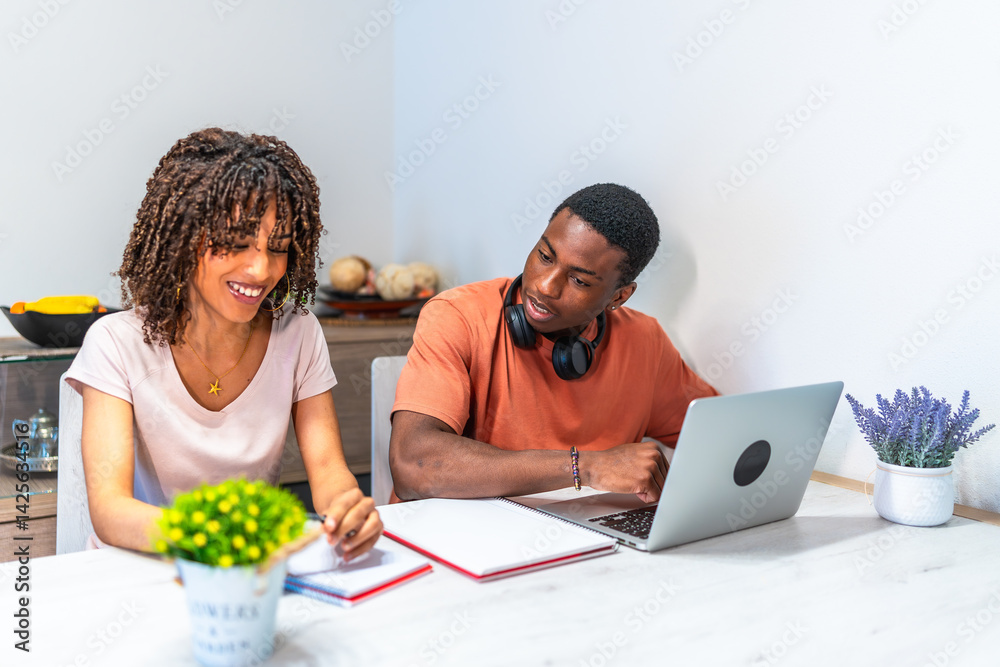 Young couple working from home using laptop and taking notes