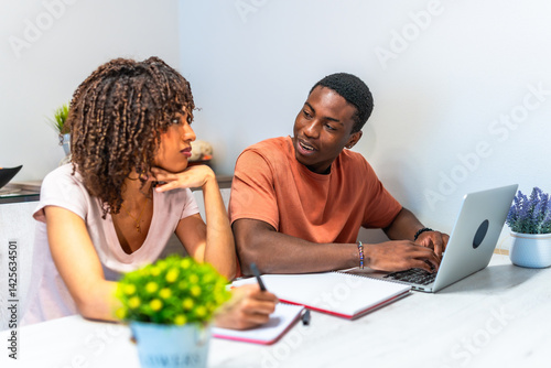 Young couple working from home are using laptop and taking notes