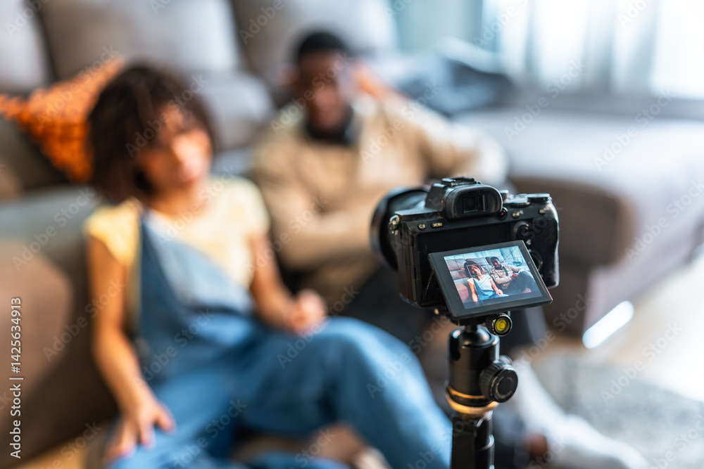 Young couple recording video content with digital camera at home