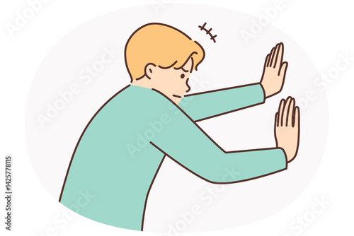 Man tensely pushes invisible wall with hands or sets himself goal of opening secret passage