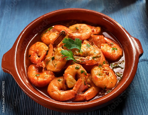 A close-up of a traditional clay cazuela filled with sizzling camarones al ajillo (garlic shrimp) showcases a flavorful seafood dish.