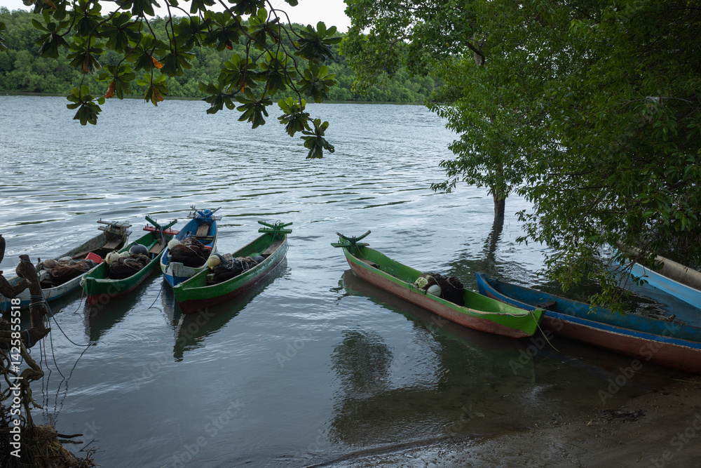 Fototapeta premium East Sumba – 04. 20. 2025 – Colorfully painted boats equipped with fishing gear are parked at the mouth of the river near the Kawangu fishing village