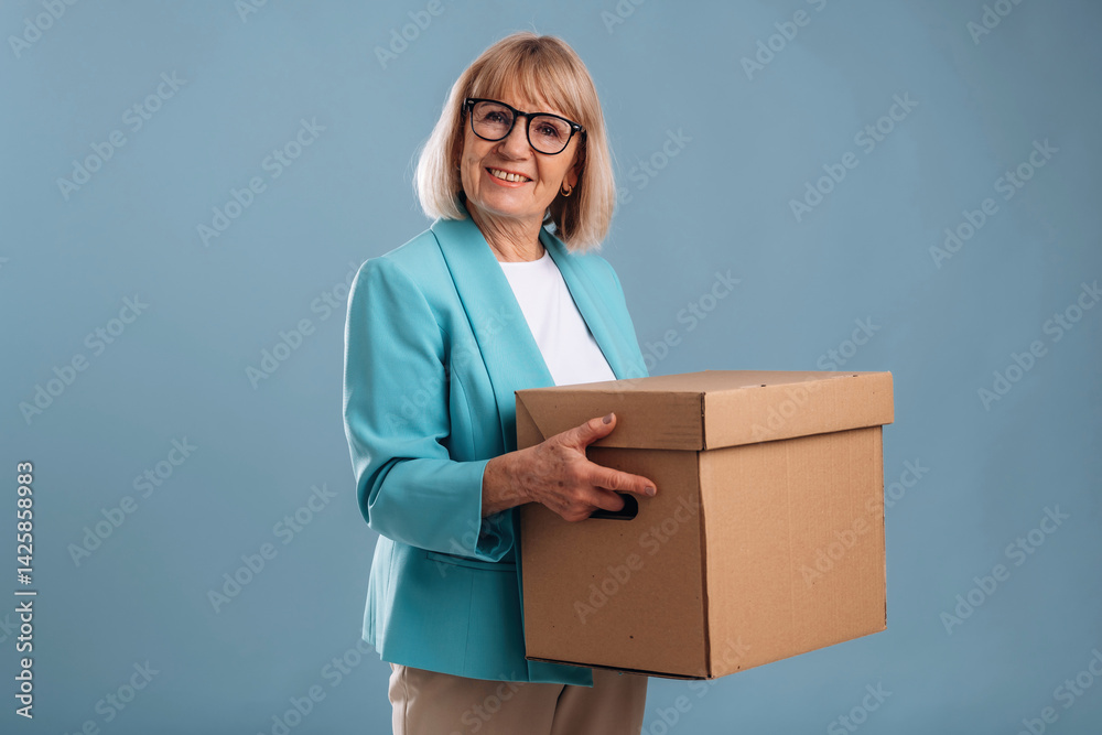 Moving conception, holding box. Senior woman is against background Moving conception, holding box. Senior woman is against background