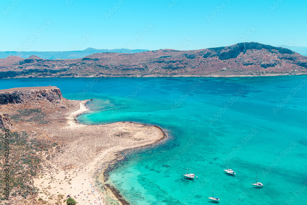 Sailboats anchored near a stunning turquoise beach