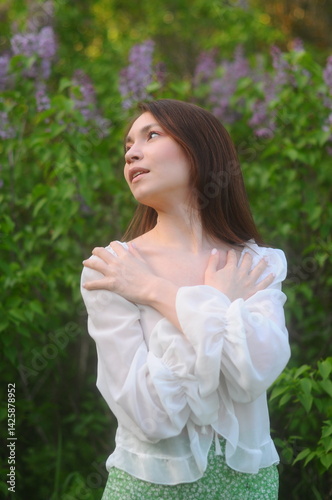 young girl walking in a summer park in a white blouse and skirt