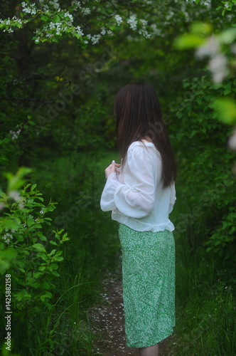 young girl walking in a summer park in a white blouse and skirt