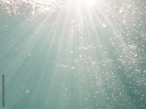 Sunrays underwater with sparkling bubbles in blue pool water 