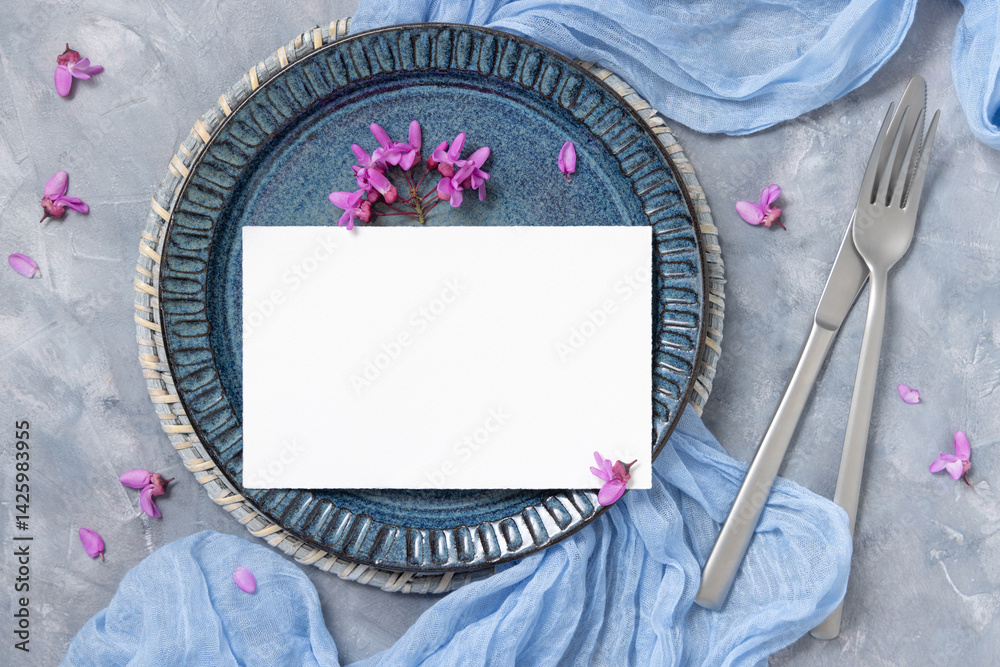 Wedding table place with a card near fabric and wild purple flowers top view on gray, spring mockup