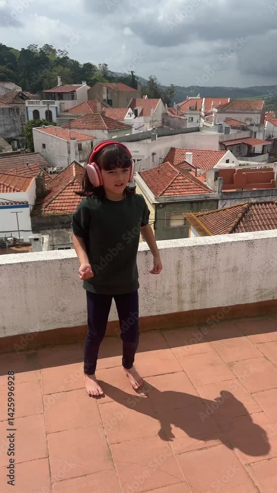 A Child Dancing Joyfully on a Rooftop While Wearing Headphones Listening to Music A Child Dancing Joyfully on a Rooftop While Wearing Headphones Listening to Music