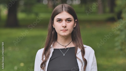 Beautiful georgian woman gracefully posing in lush green park, surrounded by blossoming trees and serene natural landscape
