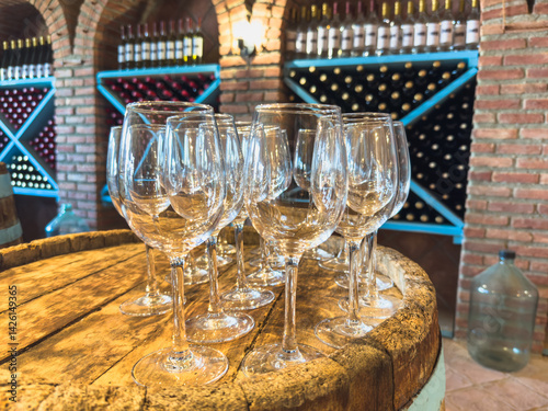 Many glasses of white wine on wooden barrel. Wine tasting event. Wine cellar with wine barrels. French wooden barrels. Wine shop wine bar winery or wine tasting concept