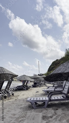 A tranquil beach scene featuring lounge chairs and umbrellas on golden sand under a bright blue sky. Sile, Turkey. Black Sea view