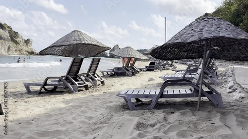 A tranquil beach scene featuring lounge chairs and umbrellas on golden sand under a bright blue sky. Sile, Turkey. Black Sea view