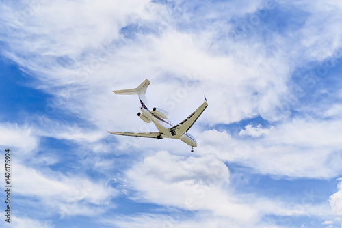 Private business plane flying under a blue sky with white clouds	