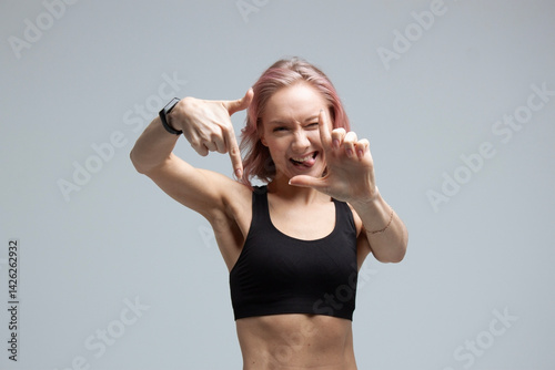 A young woman on a gray background shows different emotions, with her face and gestures. human mood