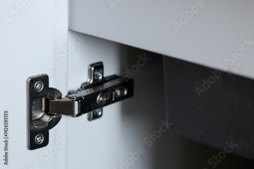 Obraz na płótnie Close-up of kitchen cabinet hinge and accessories with white storage cabinet and sink in the background. perfect for home improvement, kitchen design, and modern storage solutions w salonie