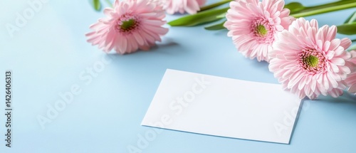 Muttertag Geburtstag Feiertag Grußkarte - Weisses leeres Papier und Gerbera Blumen auf blauem Hintergrund photo
