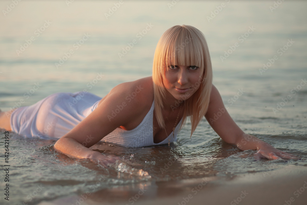 Obraz premium woman at sunset in the water in white dress