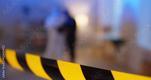 Close up cropped view of bright caution tape marking restricted area of crime scene on blurred background with red blue lights flashing. Police investigation, evidences gathering, forensic examination
