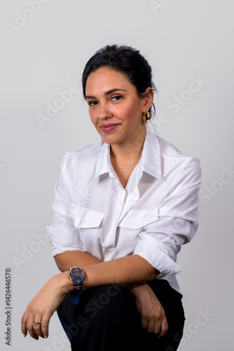 Obraz na płótnie A woman is sitting on a chair and wearing a white shirt and black pants w salonie