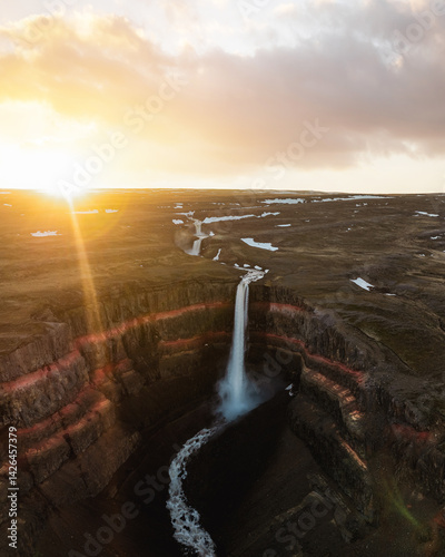 Obraz na płótnie Aerial shot of Hengifoss waterfall at sunset, highlighting vivid red rock layers and dramatic cliffs in Iceland’s remote eastern highlands. w salonie