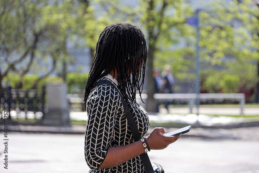 African woman using mobile phone on city street, smartphone in female hands