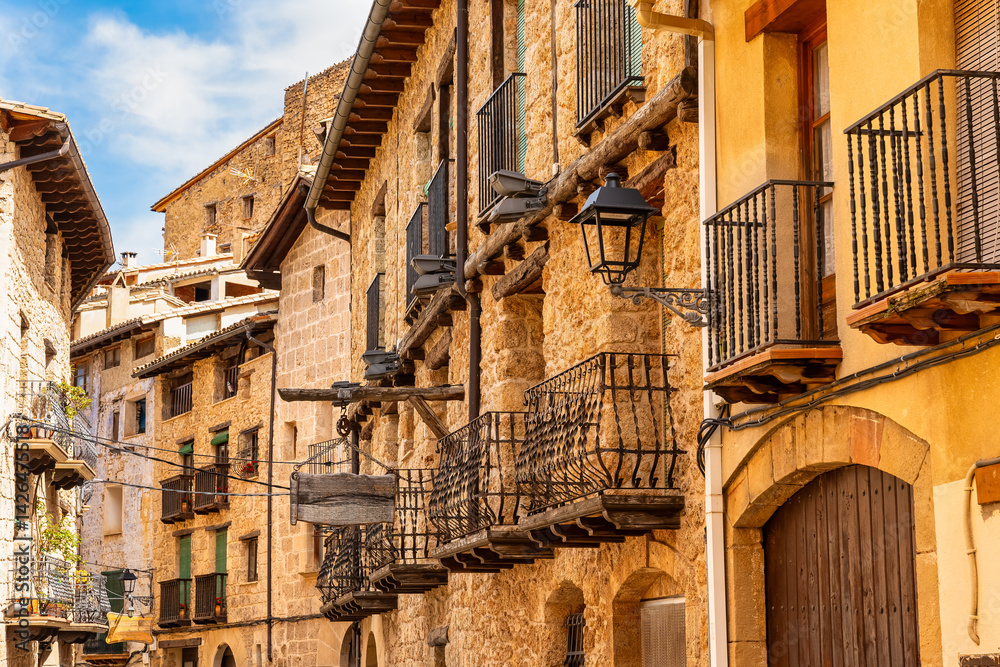Main street of Beceite with stone houses and balconies of bars in a medieval-looking village, Teruel.