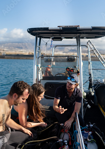 Diving instructor explaining scuba diving equipment on boat to tourists