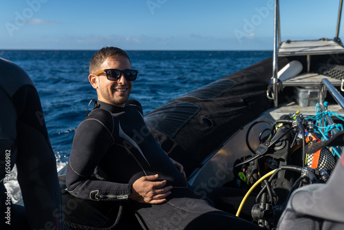 Smiling scuba diver relaxing on inflatable boat, ready for diving adventure