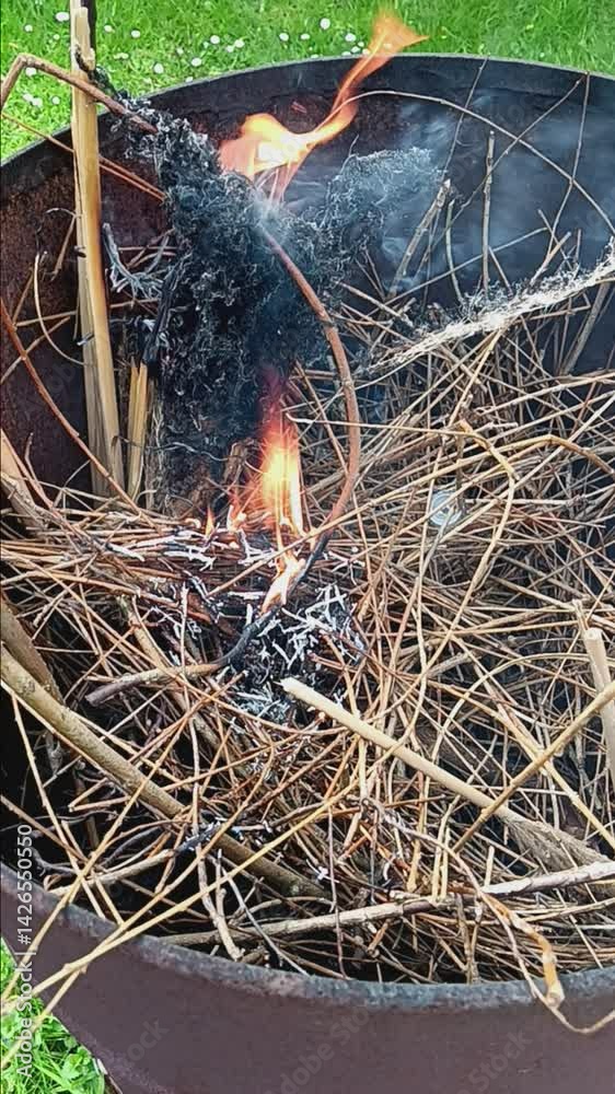 Verbrennung von Gartenabfällen in einer rostigen Feuertonne.