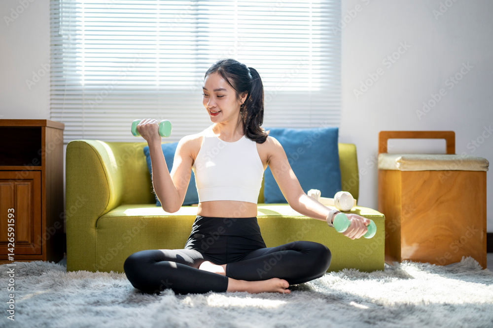A woman is sitting on a green couch and holding two dumbbells