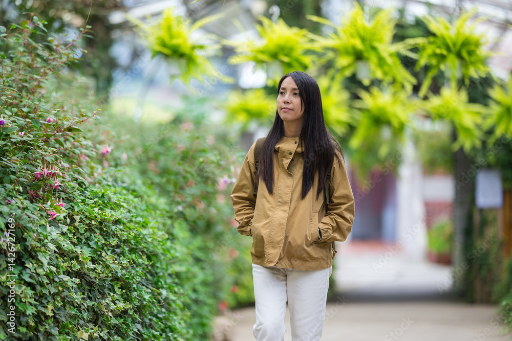 Young woman strolls along peaceful garden walkway